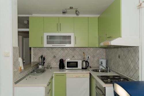 a kitchen with green cabinets and a microwave at Sarajevo Central View Apartment in Sarajevo
