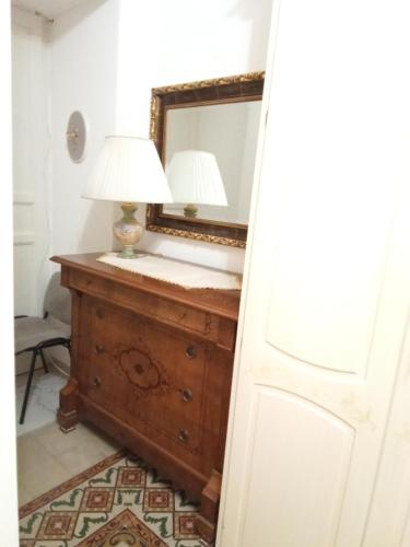 a room with a mirror and a dresser with a lamp at Adriana's home in Caltanissetta