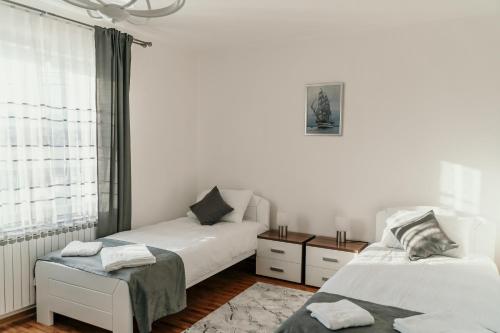 a white bedroom with two beds and a window at Sarajevo Central View Apartment in Sarajevo