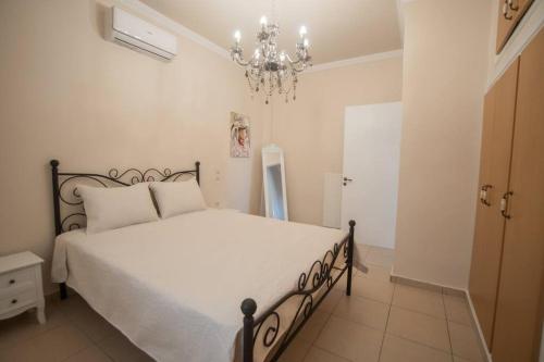 una camera da letto con un grande letto bianco e un lampadario a braccio di Mulberry tree villa ad Ágios Nikólaos