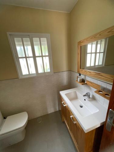 baño con lavabo y aseo y ventana en LA BARROSA VILLA, en Chiclana de la Frontera
