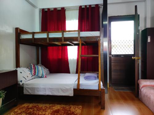 1 dormitorio con 2 literas y cortinas rojas en Terrazas de Miguel Apartment, en Iriga City