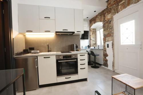 a kitchen with white cabinets and a stove at Stones By Syros Bnb in Ermoupoli