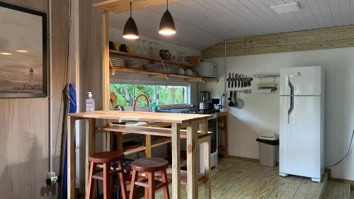 a kitchen with a wooden table and a refrigerator at Um Paraiso entre a Floresta e o Mar in São Francisco do Sul