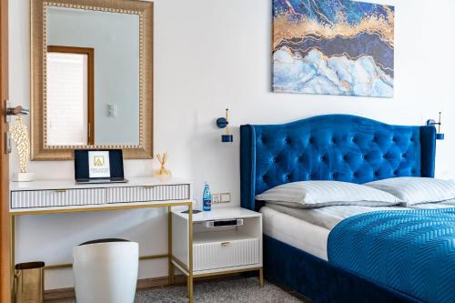 a bedroom with a blue bed and a mirror at Grelewicz Apartments-MyView in Toruń