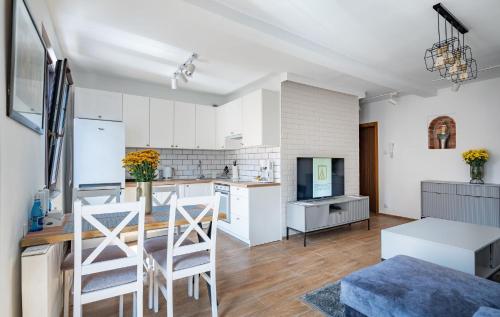a kitchen with white cabinets and a table and chairs at Grelewicz Apartments-MyView in Toruń