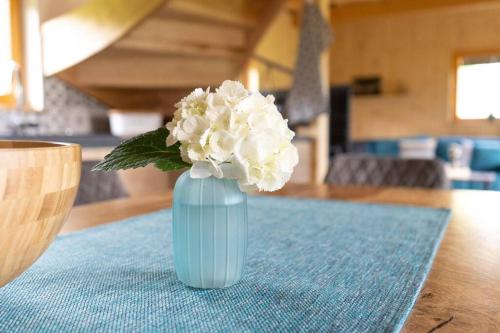 un jarrón azul con flores blancas sentado en una mesa en A Nest Under the Karawanks, en Žirovnica