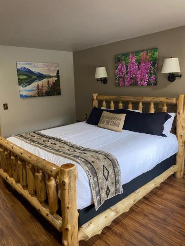 Un dormitorio con una cama de madera con sábanas blancas y flores en Summit Lake Lodge, en Summit Lake