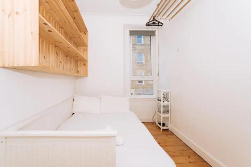 uma pequena cozinha com paredes brancas e armários de madeira em Sleek & Central 2BD Flat - Haymarket em Edimburgo