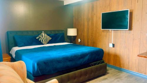 a bedroom with a blue bed and a flat screen tv at Crestwood Motel in Burlington