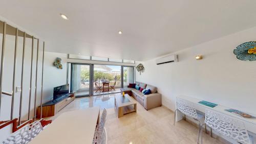 a living room with white walls and a table and chairs at LES LAURIERS - PISCINE SUR LE TOIT - ANSE MARCEL in Anse Marcel 