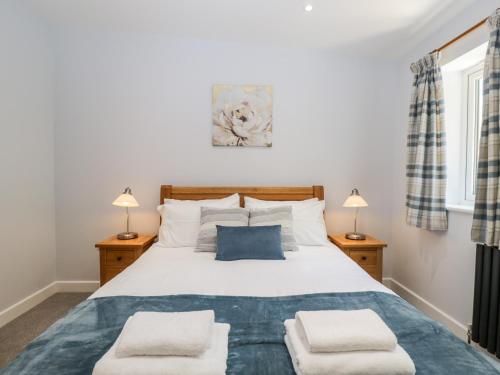 um quarto com uma grande cama branca e 2 candeeiros em Stag Cottage em Poole