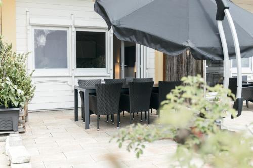 a patio with a table and chairs and an umbrella at HEIMATEL - Suiten, Apartments und Studios in Scheidegg