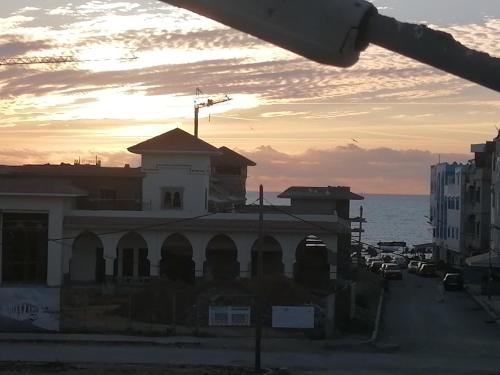 un edificio en una calle con el océano en el fondo en Younes residence, en Asilah