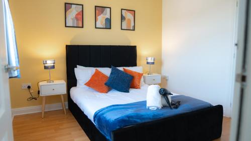 a bedroom with a bed with orange and blue pillows at Modern Marvel in Whaddon