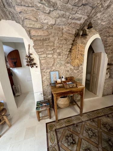 um quarto com uma mesa e uma parede de pedra em DOMMO ASULETTA em Bosa