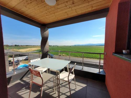 a table and chairs on a balcony with a view of a field at Cocon zen et confortable à proximité de Colmar in Sundhoffen