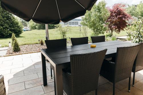 a black table and chairs with an umbrella at HEIMATEL - Suiten, Apartments und Studios in Scheidegg
