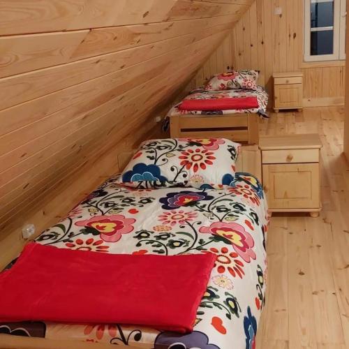 two beds in a room with wooden walls at Malowany Domek in Przymiłowice