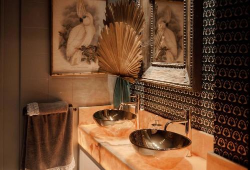 Baño con 2 lavabos y cuadros en la pared en Villa Tela & Vino, en Montilla
