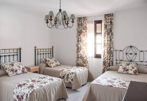 1 dormitorio con 2 camas y lámpara de araña en Villa Tela & Vino, en Montilla