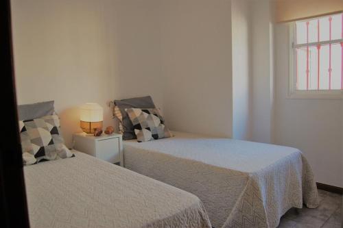 Un dormitorio con dos camas y una ventana. en Mágnifico ático a escasos 100 metros de la playa!, en Torre del Mar