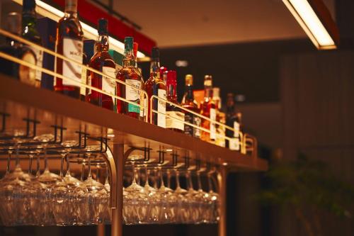a row of wine bottles and glasses on shelves at voco Osaka Central by IHG in Osaka