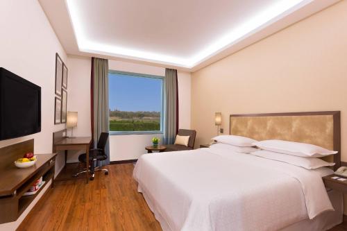 a hotel room with a large bed and a large window at Four Points by Sheraton New Delhi, Airport Highway in New Delhi