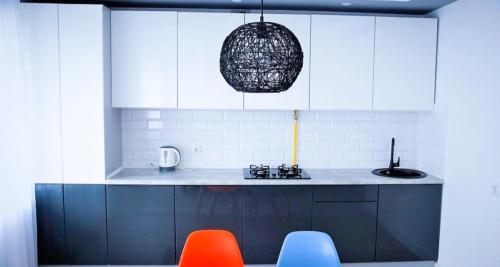 a kitchen with orange and blue chairs and white cabinets at Esplanada aparments in Sumy
