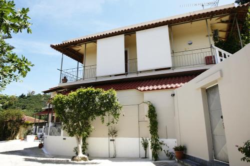 a white house with a tree in front of it at Petros Giatras - Rooms in Zakynthos Town