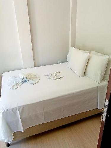 a white bed with white pillows and bows on it at Hospedaje MorroSP in Morro de São Paulo