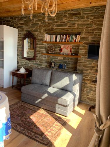 ein Wohnzimmer mit Sofa und Ziegelwand in der Unterkunft ΠΕΤΡΙΝΟ στην Άνδρο in Agia Eleousa