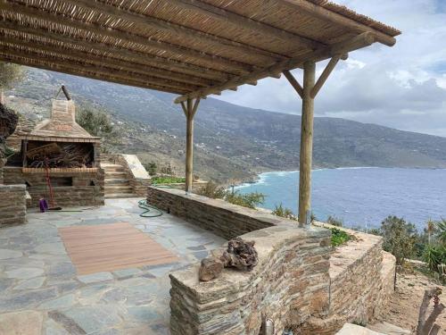 d'une terrasse en pierre avec un grill extérieur offrant une vue sur l'océan. dans l'établissement ΠΕΤΡΙΝΟ στην Άνδρο, à Agia Eleousa