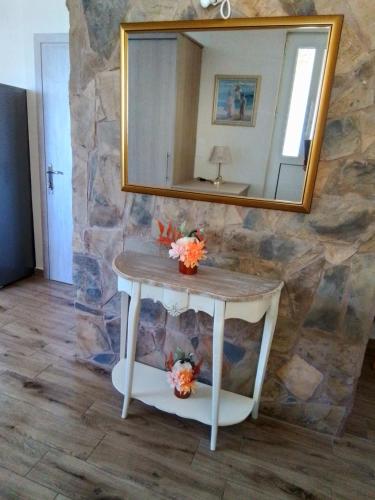 a bathroom with a table with a mirror on a stone wall at IL TRAMONTO APARTMENT 1 in Kanali