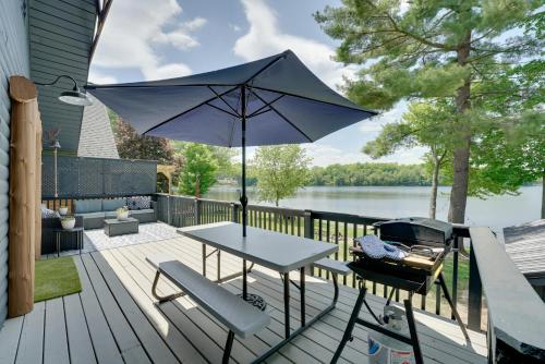 a patio with a table and an umbrella at Diamond Lake Waterfront Cabin with Deck and Dock! in Tustin