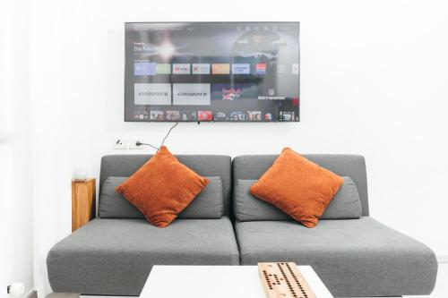 a couch with two orange pillows in a living room at Rosenalm Scheidegg in Scheidegg