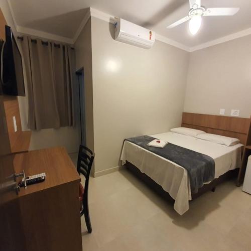 a bedroom with a bed and a desk and a table at Hotel Tertulio's in Rio Claro