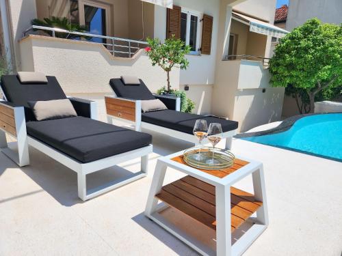 eine Terrasse mit 2 Stühlen, einem Tisch und einem Pool in der Unterkunft Calypso Royal Apartment in Zadar