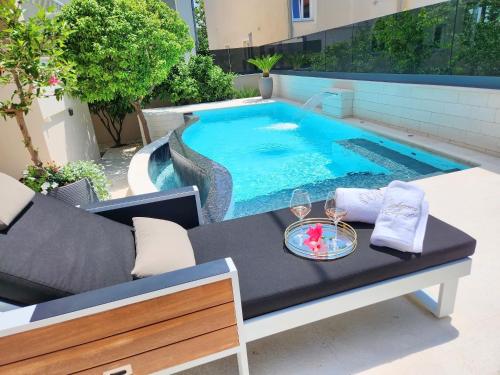een tafel met een glas wijn erop naast een zwembad bij Calypso Royal Apartment in Zadar
