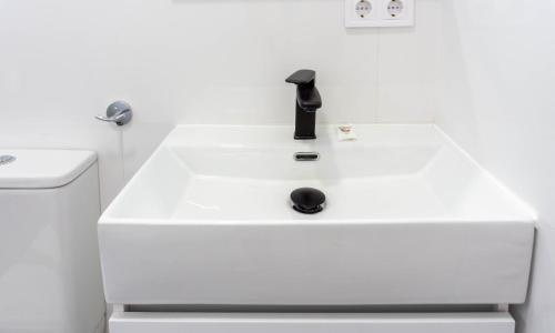 un lavandino bianco nel bagno con rubinetto nero di Sun & Luxury at Guadalmar Beach a Málaga
