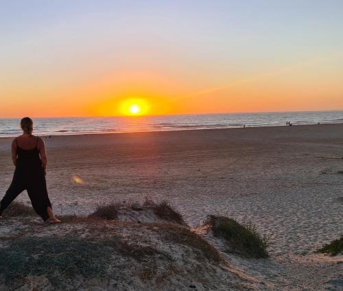 Una mujer caminando por la playa al atardecer en Seaside Serenity - Stylish Apartment with Spectacular Views en Manilva