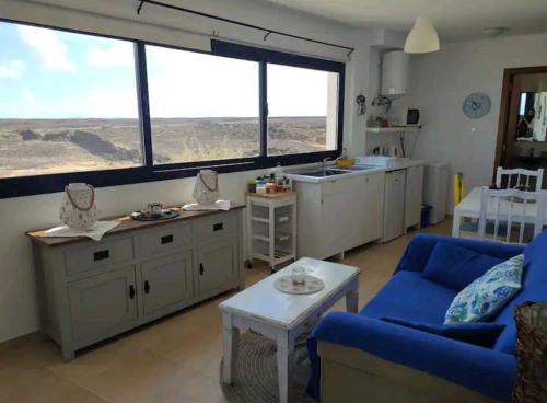 コティージョにあるCasa Maria Cotillo Marのリビングルーム(青いソファ付)、キッチン(大きな窓付)