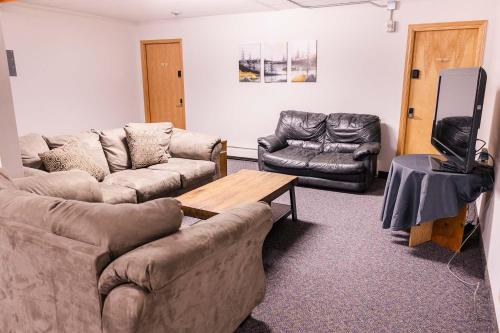 a living room with couches and a table and a tv at Delta Lodge in Delta Junction