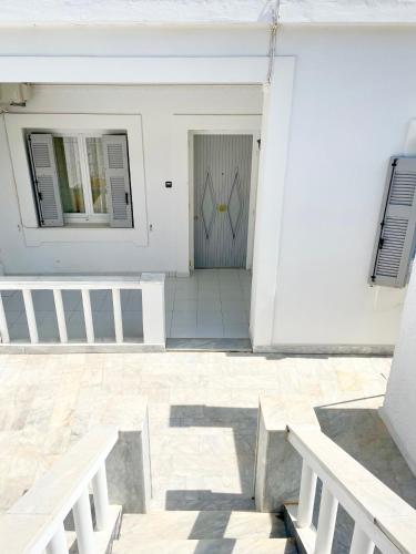 a white house with two benches in front of a door at Poseidonia's Breeze in Posidhonía