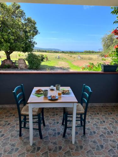 una mesa y sillas blancas con vistas a un campo en Agriturismo Graziano e Barbara, en Porto Conte