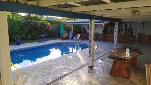 uma piscina com uma mesa e um guarda-sol em Maison de vacances avec piscine et accès plage de sable blanc em Punaauia