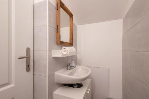 a white bathroom with a sink and a mirror at Kékmadaras Vendégház Tihany in Tihany