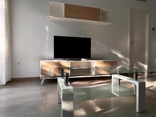 een woonkamer met een glazen tafel en een televisie bij AM DEL SOL in Fuengirola