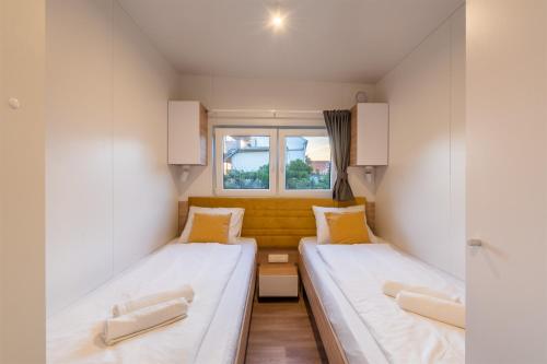 two beds in a small room with a window at Giardino Sukošan - new mobile houses in olive garden, EV plug-in station in Sukošan