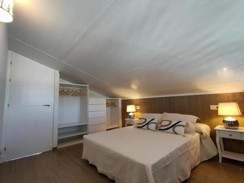 a bedroom with a large white bed with two pillows at Apartamento Mistral 5, con piscina y parking. in Chiclana de la Frontera